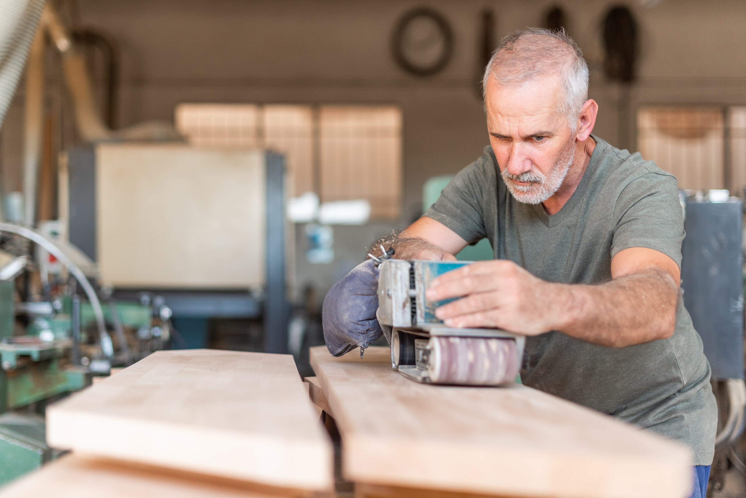 Male person focused working with a hand sander polishing a wooden board